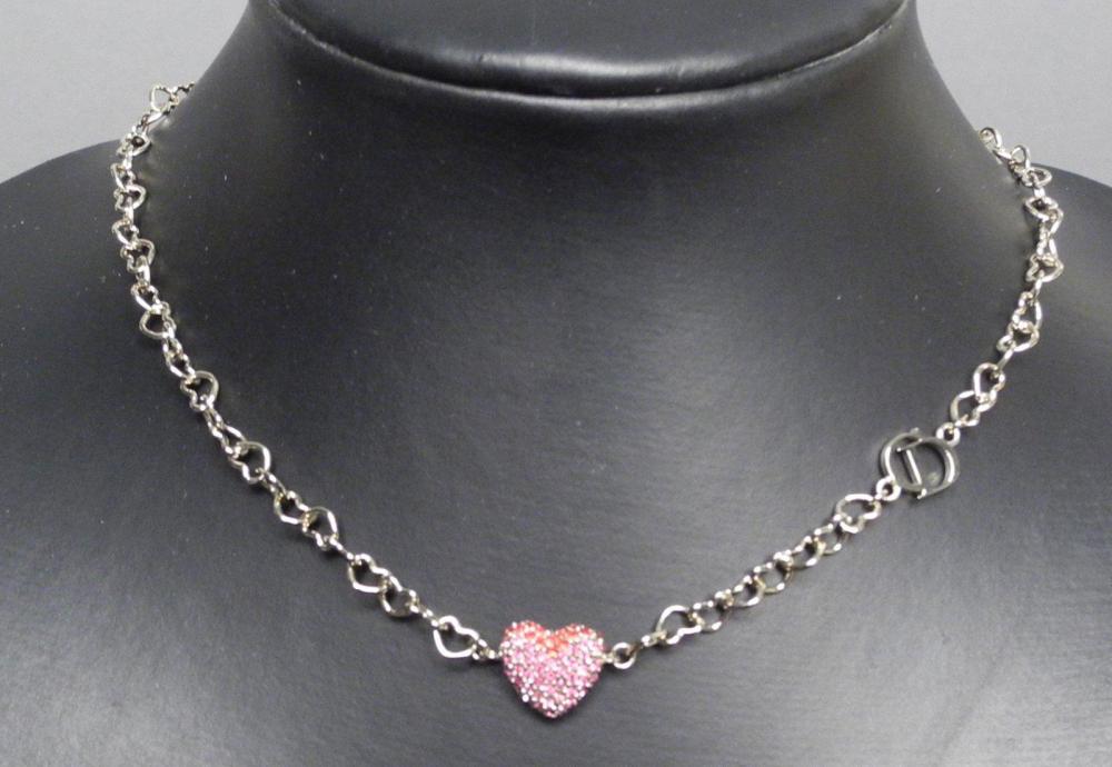 Christian DIOR

Collier ras-du-cou en métal doré composé de maillons en forme de coeurs orné d’un élément central formant un coeur pavé de strass roses Fermoir siglé ETAT NEUF Dans sa pochette et sa boîte d’origine