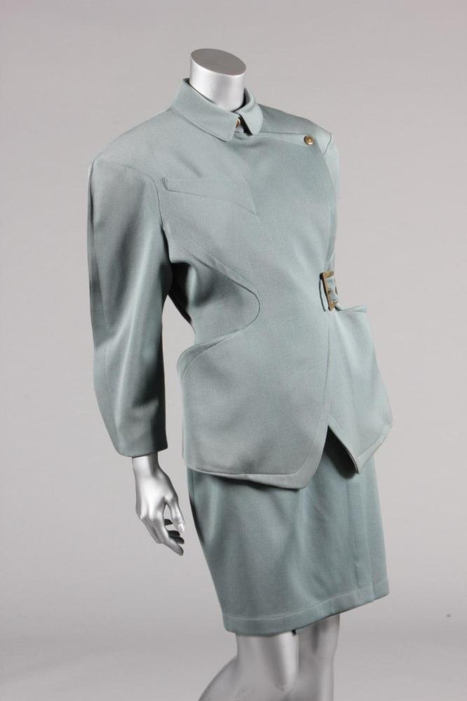 

A Thierry Mugler blue worsted suit, circa 1987, labelled and size 40, with curved seaming, with top-stitched detailing and buckle to waist, brass prestud fasteners, chest 102cm, 40in, waist, waist 71cm, 28in (2)
