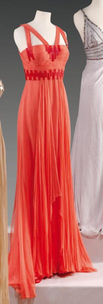 VERSACE par Donatella VERSACE, circa 2000

Robe longue en mousseline corail, haut bustier drapé à double bretelle orné de plaques de galalites à motifs géométriques et de panneaux volants, jupe longue souple Griffe noire, graphisme beige