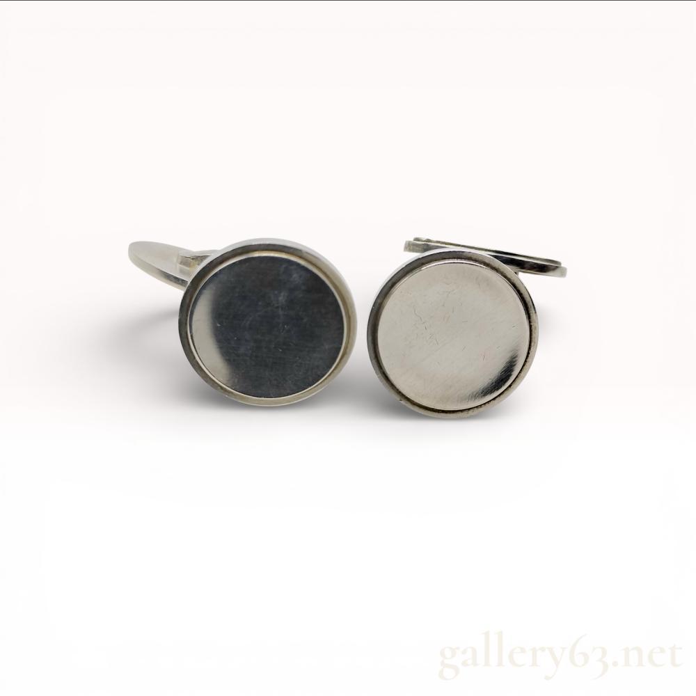 Description
Georg Jensen SV925 sterling silver cufflinks featuring round bezel-set faces.


Circular tops having smooth polished centers framed by raised silver borders.


Swivel back closures allowing secure fastening.


Undersides bearing Georg Jensen hallmarks and SV925 stamp.


Total weight approximately 17.6 grams.