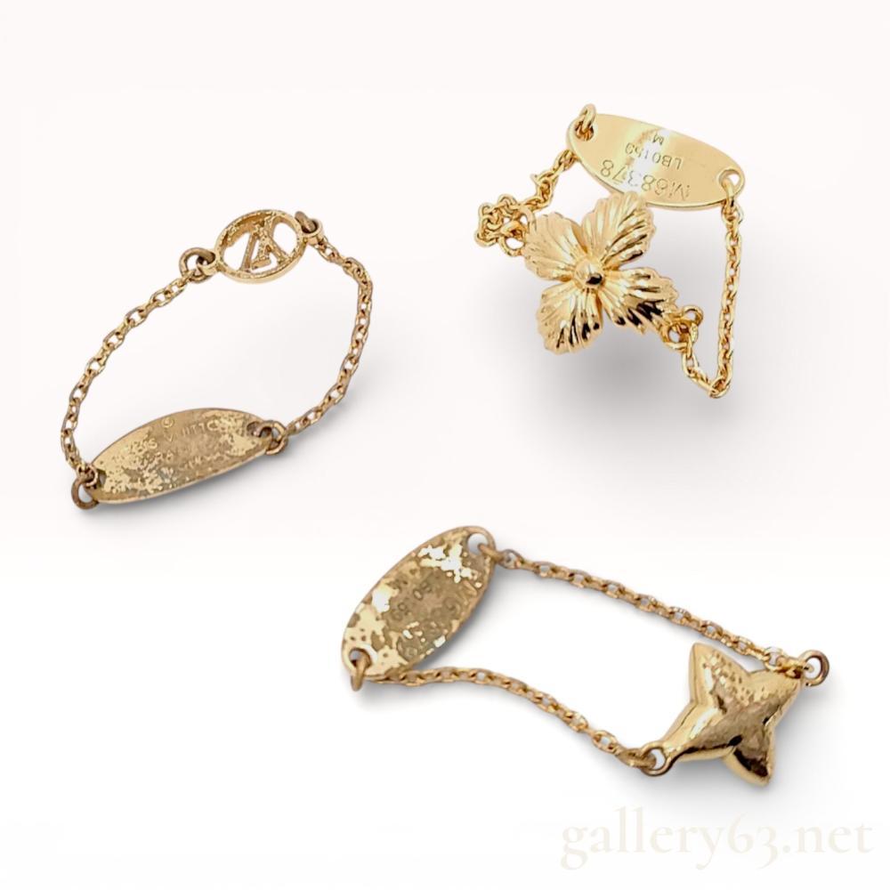 Description
Louis Vuitton Blooming ring set, model M68378, featuring three individual chain-link rings in gold-toned metal. Each piece includes a distinct motif: a textured four-petaled flower, a polished star monogram flower, and an openwork LV circle, all connected to oval identification tags by delicate link chains. The tags are marked with the Louis Vuitton Paris signature, model number M68378, production code LB0159, and size M.
Length: 20mm - 25mm.