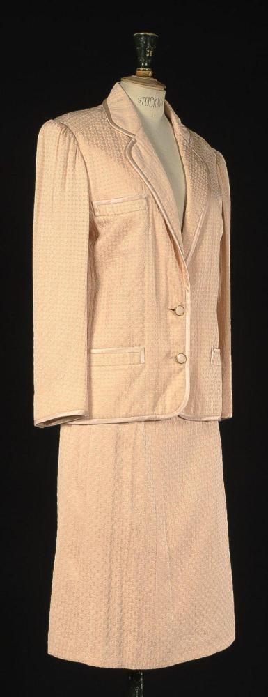Emanuel UNGARO

Patron papier, circa 1980 Tailleur en soie à effet damassé rose pâle, entièrement gansé de soie unie à la couleur, veste à col tailleur arrondi, une poche poitrine et deux poches passepoilée, manches longues, jupe évasée. Griffe blanche, graphisme noir (manque un bouton)
