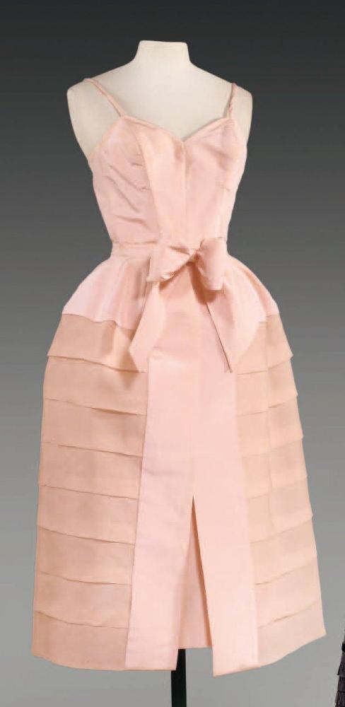 Emilio SCHUBERT Roma, circa 1950

Ensemble de cocktail en reps de soie rose comprenant une robe de forme droite à bretelles se portant sous une jupe large fendue à plis plats à partir des petites hanches en organza sur crin de même couleur, taille soulignée d’un noeud. (coutures de la robe non d’origine) Griffe blanche, graphisme noir