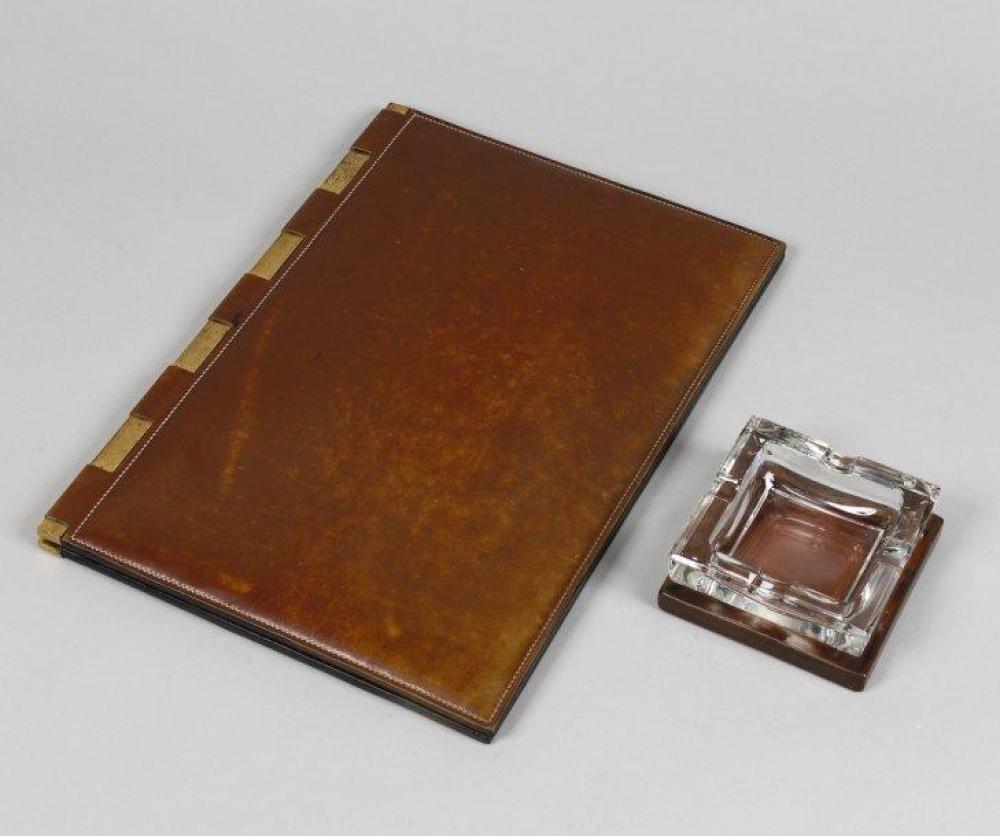 HERMES Paris

24 faubourg St Honoré, travail Dupré-Laffont *Sous main à abattant ouvrant en cuir fauve, réhaussé d’une surpiqûre blanche, à charnière en métal doré et un cendrier en cuir fauve et cristal