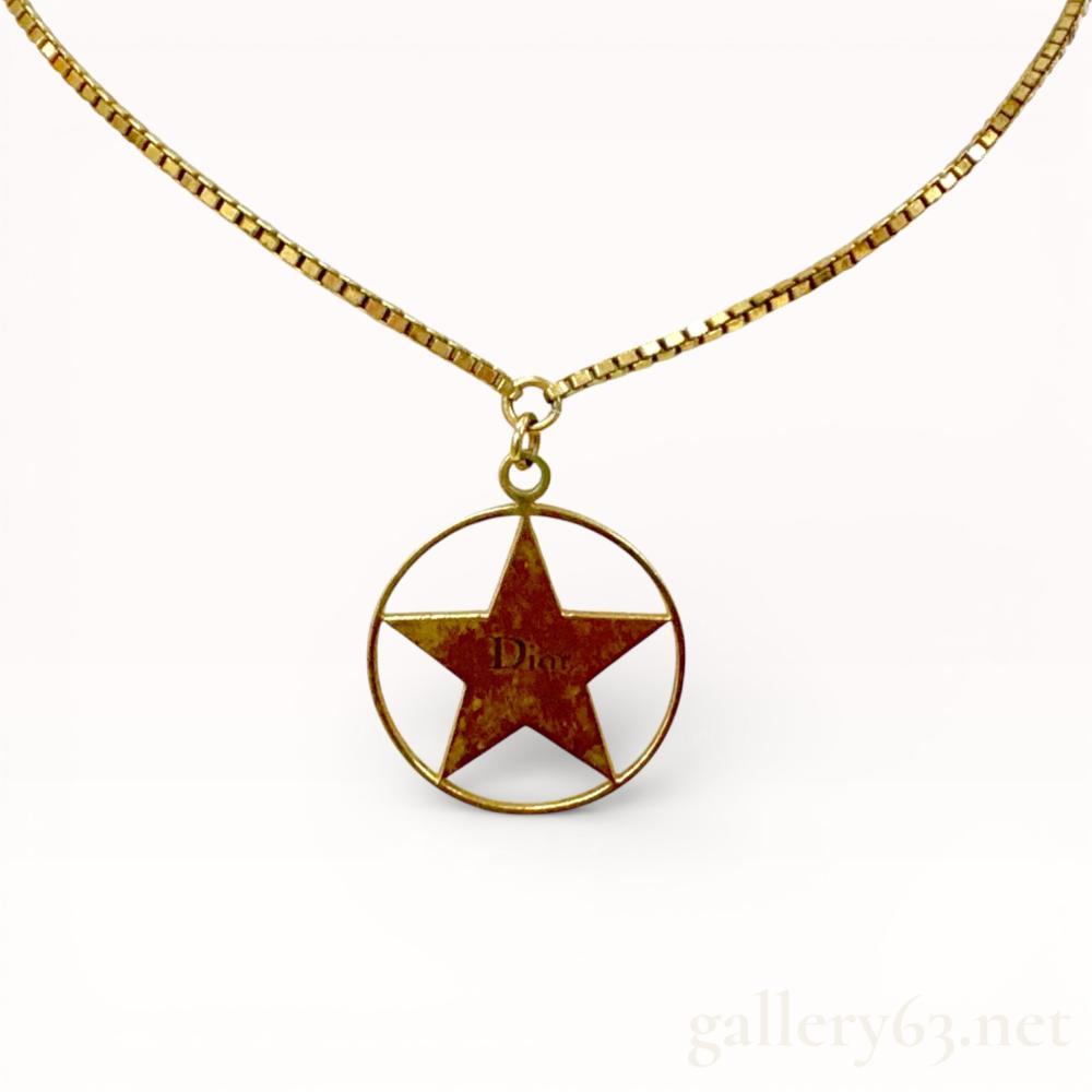Description
Authentic  Dior necklace featuring a gold-tone box link chain suspending a circular pendant. Pendant formed with an open round frame enclosing a five-point star motif at center. Star finished in a contrasting brown tone with Dior branding visible across the surface. Pendant attached with a simple jump ring and finished with an adjustable clasp. Design presenting a graphic star emblem with balanced proportions throughout.