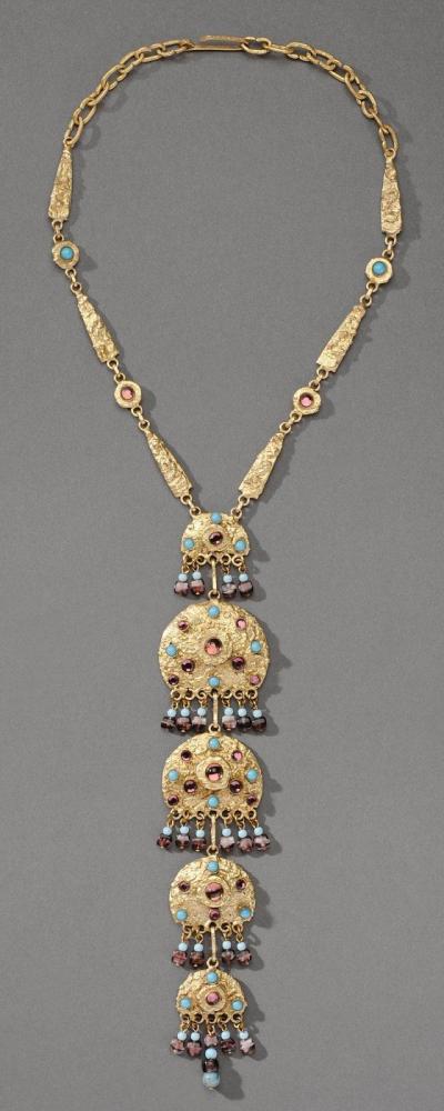 HENRY - circa 1960

Collier articulé en bronze doré composé de cinq éléments orné de cabochons à l’imitation d’améthystes et de turquoises se finissant par des pampilles de perles Fermoir crochet Signé au revers d’un des éléments