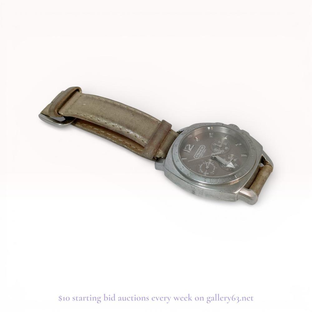 Description
Coach multi-function quartz wristwatch featuring a silver-tone sunray dial with three sub-dials indicating day, date, and 24-hour time. The stainless steel case is designed with an engraved bezel repeating the brand logo and is fitted to a metallic taupe fabric-covered leather strap. The dial bears the Coach Est. 1941 signature, and the screw-down case back is marked with model number CA.13.7.14.0431 and 3ATM water resistance.
Case size: 38mm.
