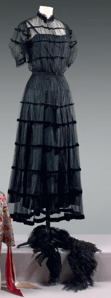 Jeanne LANVIN

Robe en tulle noir orné de rubans de velours de même couleur, encolure ronde soulignée d’un ruché, manches courtes ballons, jupe ample. (petits trous). Nous y joignons un fond de robe portant la griffe Jeanne Lanvin n°54336, Automne - Hiver 1928 / 1929 ainsi qu’une étole en plume noire