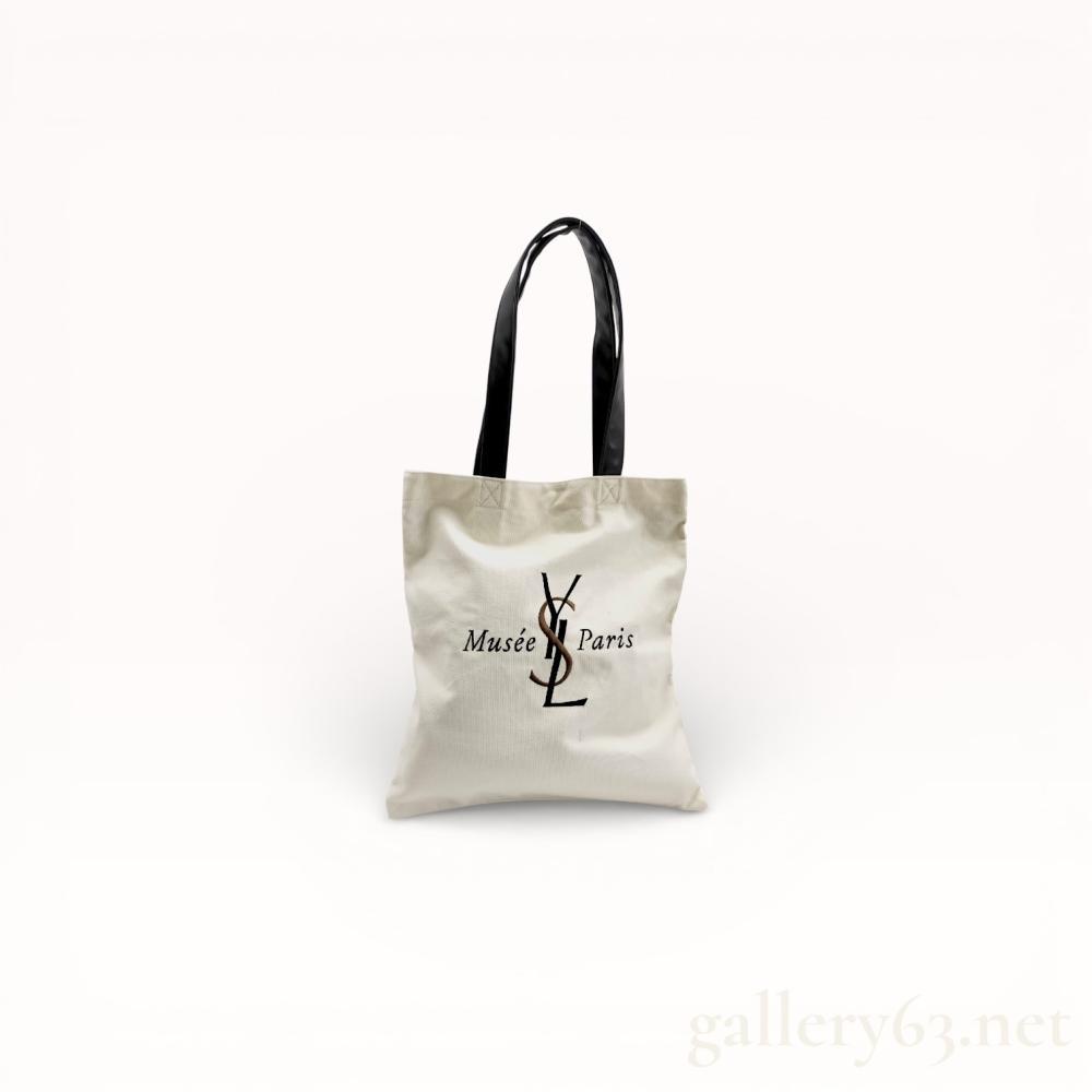Description
Musee Yves Saint Laurent Paris canvas tote bag, an official souvenir item from the museum. The exterior is crafted from cream-colored heavyweight canvas with a printed logo and black synthetic leather straps reinforced with X-pattern stitching. The interior is lined with black fabric and features a single zippered pocket with branded ribbon trim and a gold-tone pull.
14 inches H x 13 inches W.