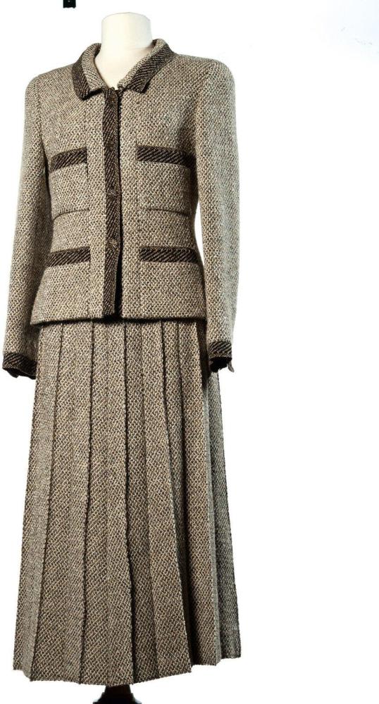 CHANEL

BOUTIQUE Tailleur en tweed de laine beige, marron et brun, entièrement gansé de bandes de tweed à diagonales dans les coloris, veste à petit col, simple boutonnage, quatre poches plaquées, manches longues, jupe à effet de plis par des surpiqûres inversées
