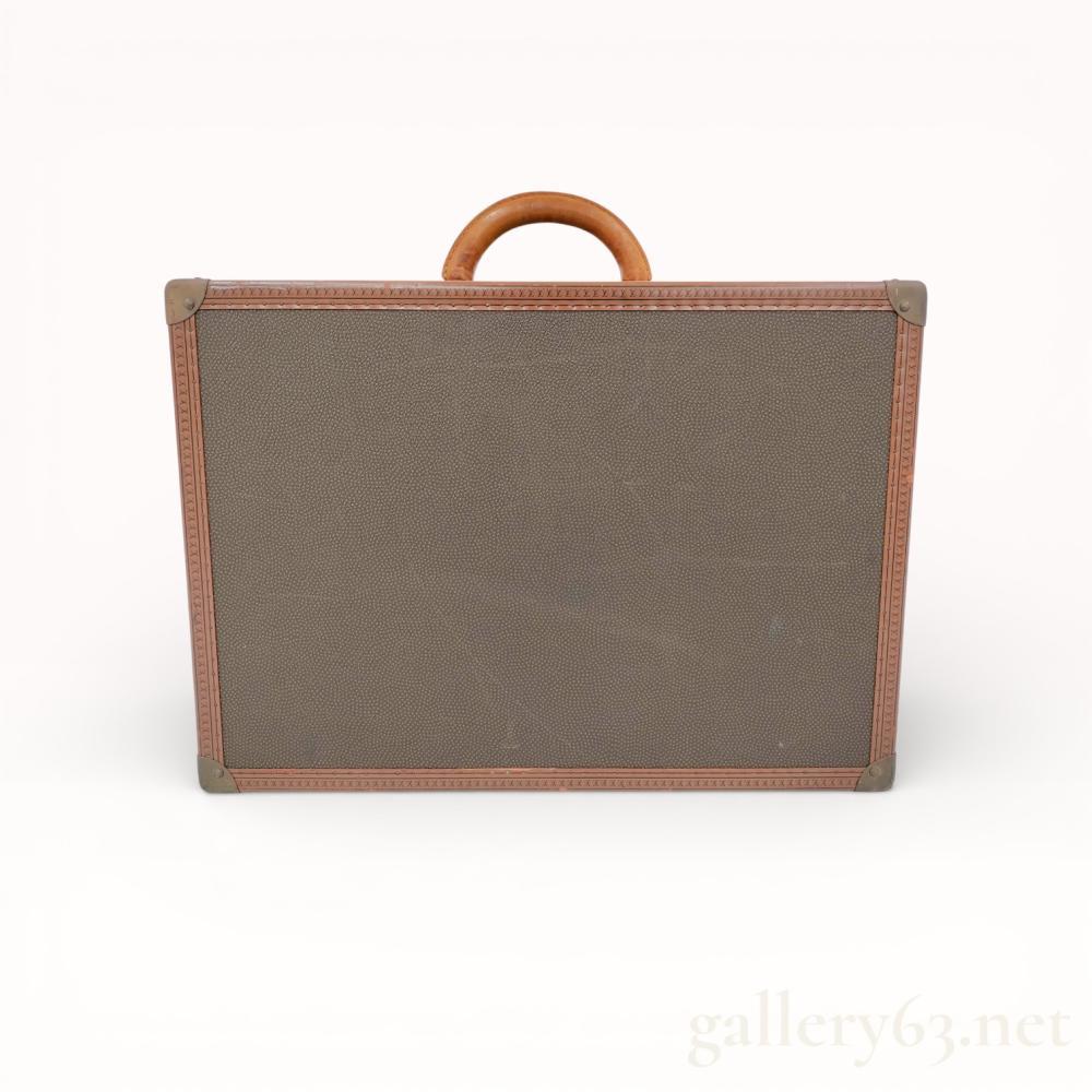 Description
Louis Vuitton vintage hard-sided suitcase, France, mid-to-late 20th century. The exterior features a textured grained canvas with LV embossed protective trim and a hand-stitched vachetta leather top handle. Brass-tone hardware includes a central locking mechanism and dual side latches with logo stamps, opening to a cream-lined interior with woven Louis Vuitton security straps. A manufacturer label is affixed to the interior rear wall.
Width: 23.5 inches.