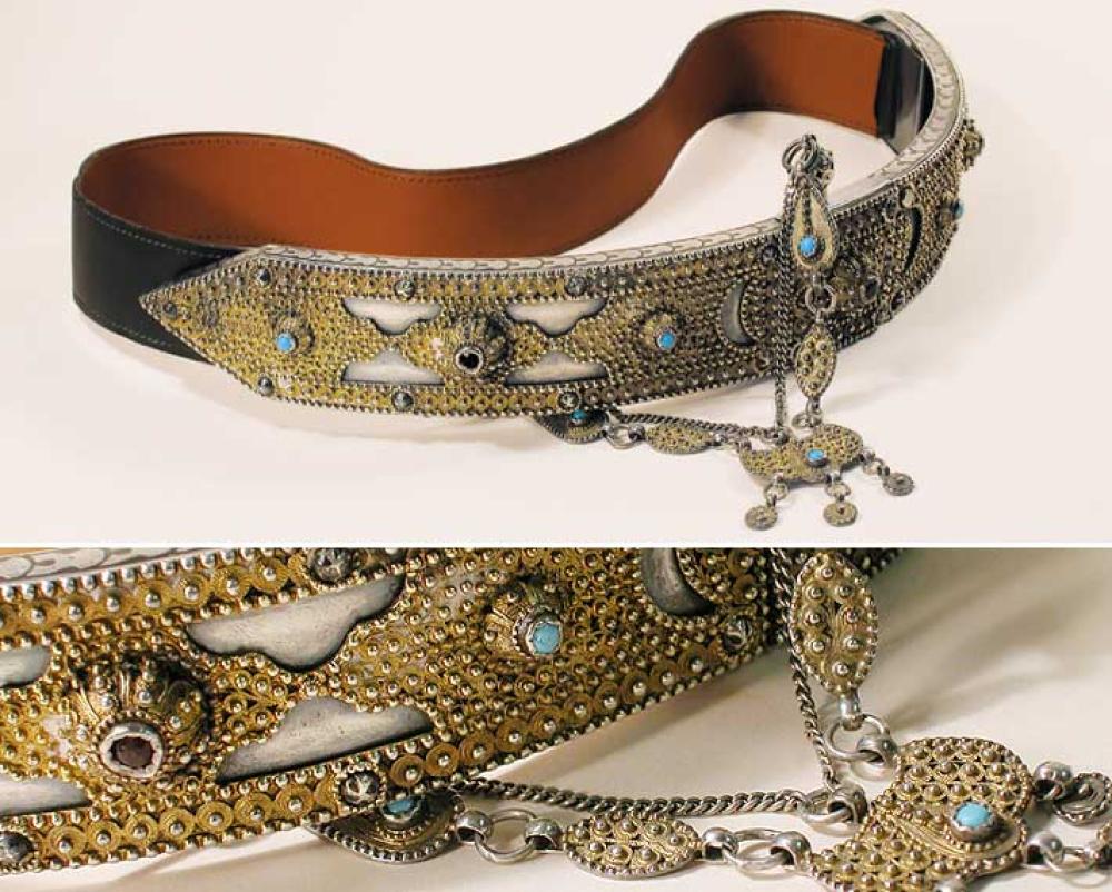 Unique Ethnic Belt with Hermes Strap

Lot 883
Unique Ethnic Belt with Hermes Strap
 Antique handmade silver front panel, Middle Eastern, adorned with studs and various metalwork emblems such as half moon and stars, inlaid with turquoise and ruby glass stones, attached chain with hole and pin closure, each half signed: T, khaki leather back strap specially made by Hermes, length adjustable/30 inches, labeled: Hermes/Paris.
Excellent condition.