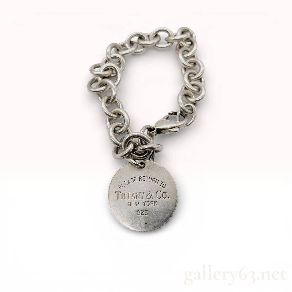 Description
Tiffany and Co. sterling silver Return to Tiffany round tag bracelet, modern period. The piece features a classic round link chain supporting a circular charm and is secured with a lobster claw clasp. The tag is engraved with PLEASE RETURN TO TIFFANY and CO. NEW YORK 925, with additional 925 hallmarks present on the clasp and jump ring.
Length: 7.5 inches
Charm Diameter: 1 inch.