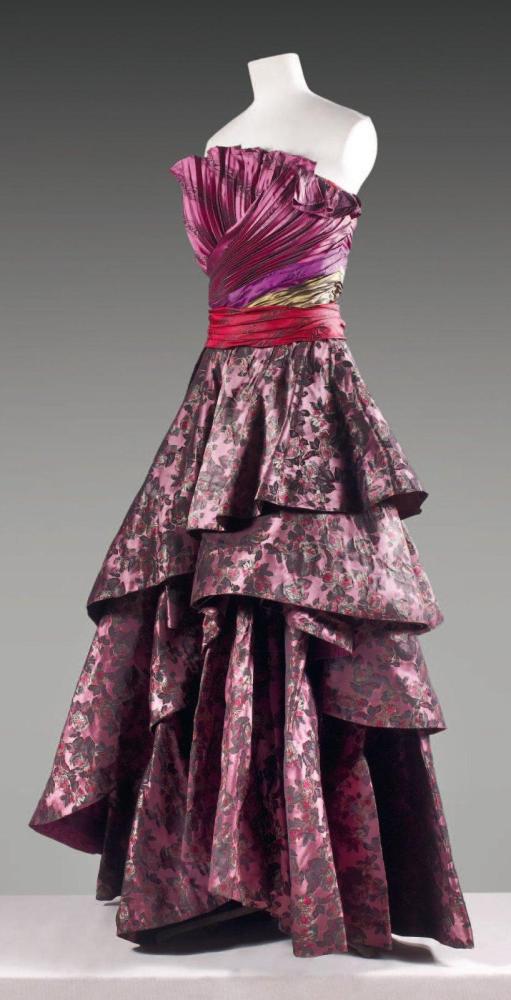 Raffaella CURIEL, circa 1978 / 1980

Robe grand soir, haut bustier croisé à plissé permanent en taffetas lie de vin imprimé d’un motif abstrait, ceinture tricolore kaki, violet, bordeaux drapée apliquée sur une jupe ample à superposition de panneaux asymétriques à motif floral. Griffe grise, graphisme blanc