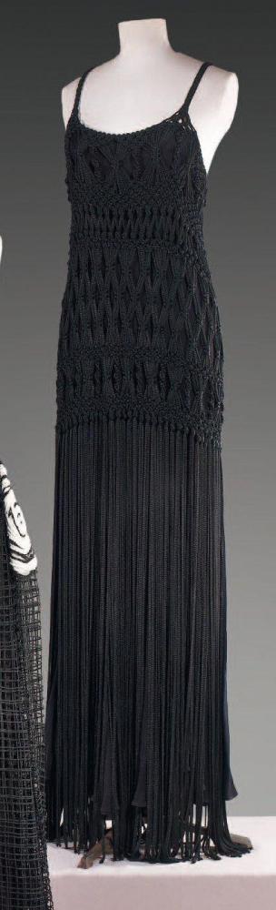 Alberta FERETTI, circa 1990

Robe longue à bretelles en jersey de soie polyester noir travaillé façon macramé, finition à partir des hanches par de longues franges Griffe blanche, graphisme noir