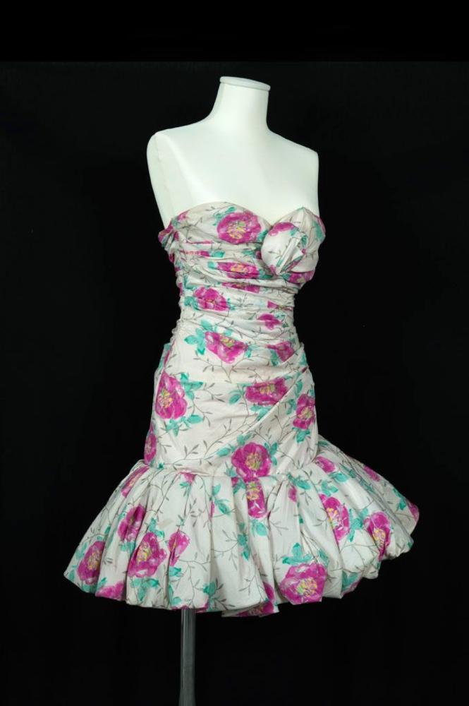 UNGARO Parallèle

Robe de cocktail en soie imprimée à motif florale multicolore sur fond blanc, haut bustier drapé et orné d’une fleur de même tissu, bas de la robe orné d’un volant à plis doublé de crinet une partie de jupe bouillonée
