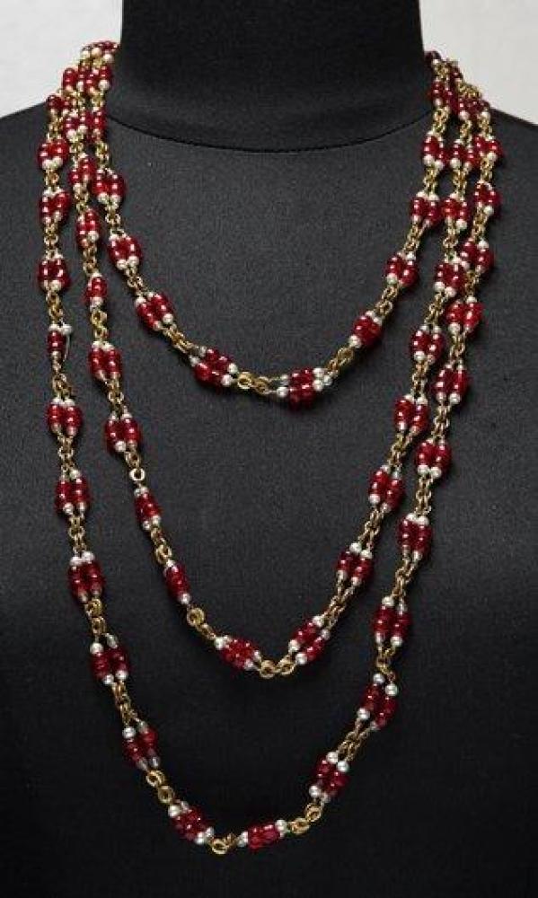 CHANEL

Haute couture circa 1954-1971 Très long sautoir à effet de deux rangs composés de petites perles de verre à l’imitation rubis, de perles blanches entrecoupées de maillons de chaines dorée. Non signé