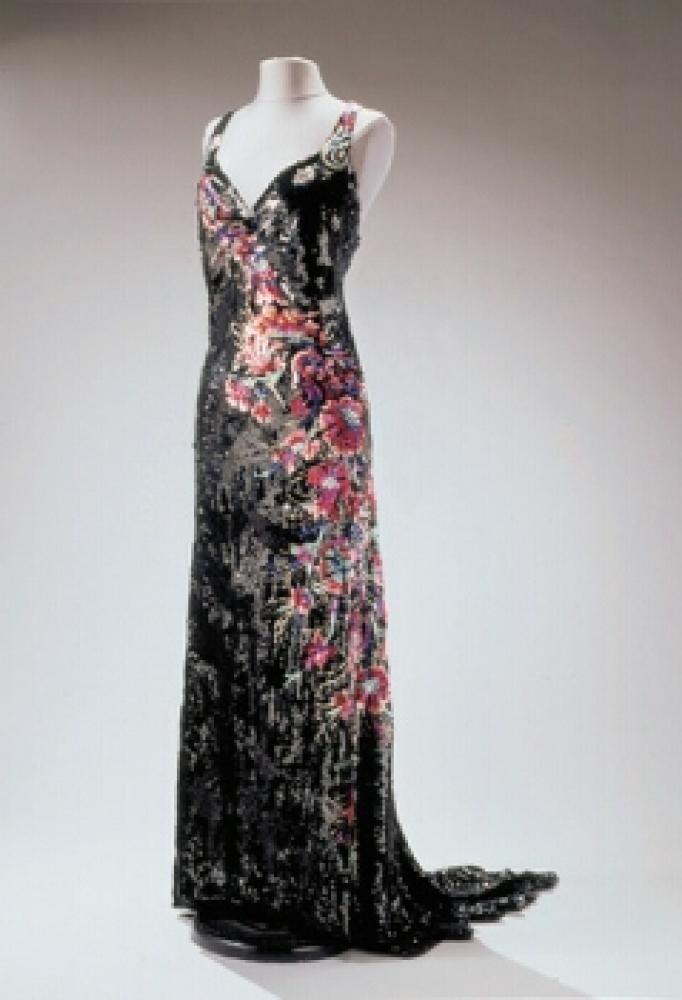 Worth Floral Spray Sequined Gown

Lot 520
Worth Floral Spray Sequined Gown
 French, 1930s 
 The sheath with sweetheart neckline and low back, square train, black tulle embroidered with black sequins arranged in swirl pattern and brilliant pink floral spray crossing diagonally at front and down left side, size 6: Worth woven in interior waistband. 
Very good condition, minor alterations at each side.