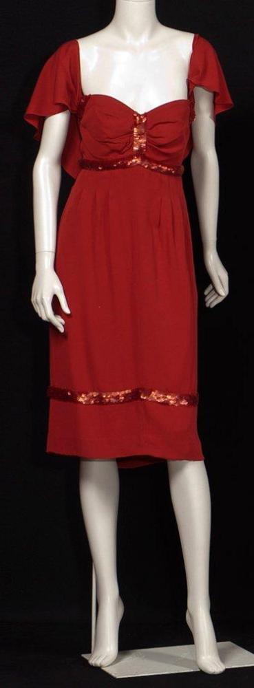 CHANEL circa 2003

Robe de cocktail en crêpe georgette rouge, effet de taille haute sur un bustier drapé souligné de paillettes de même couleur, encolure américaine soutenant une cape, jupe droite, avec rappel des paillettes, poches dans les coutures
