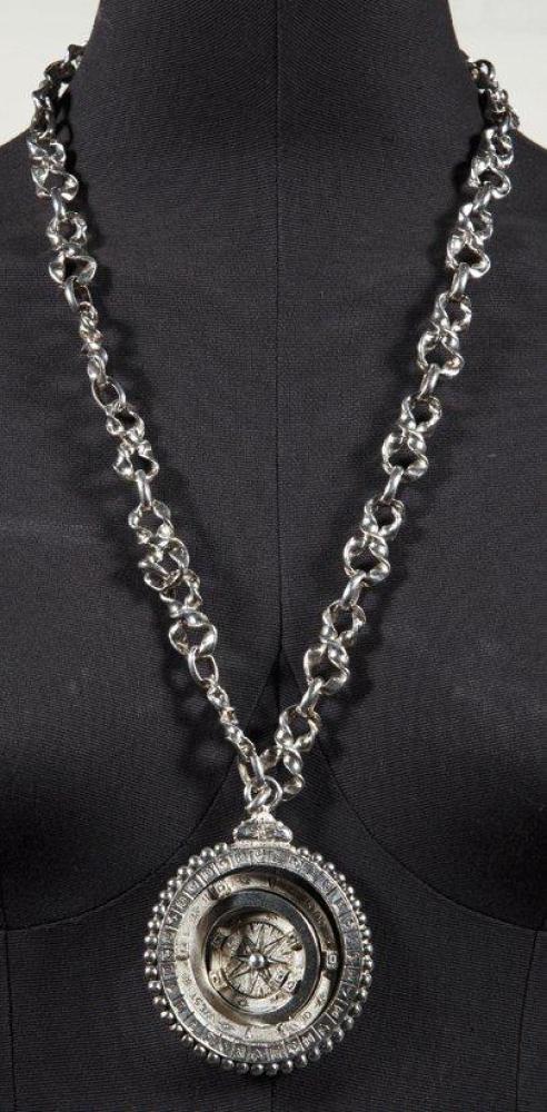 YVES SAINT LAURENT

Magnifique pendentif articulé en métal argenté figurant une sphère armillaire sur un sautoir chaîne à maillons fantaisie, fermoir par trois petits coeurs. Signé