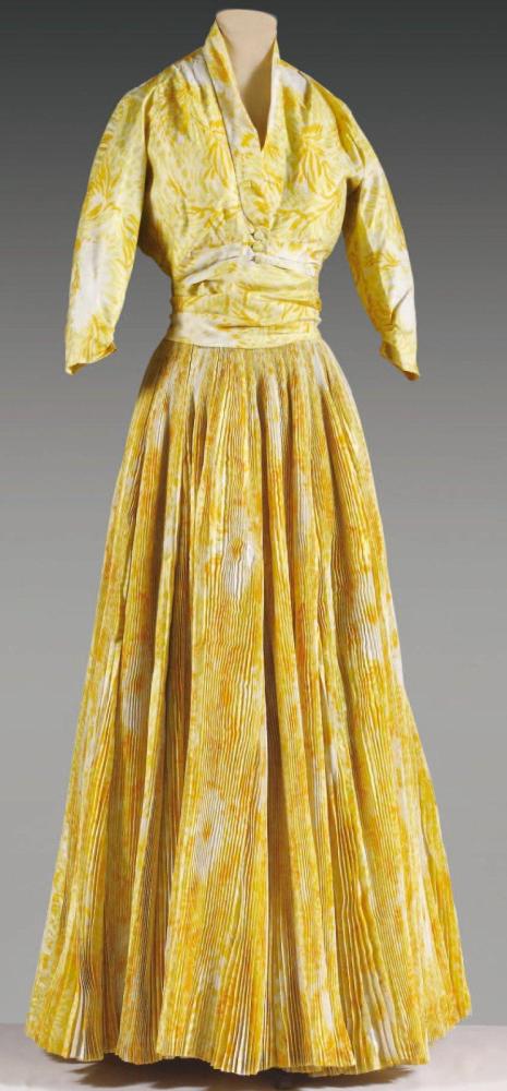 Christian DIOR

Ensemble du soir en shantung de soie imprimé à motif floral blanc, orange sur un fond bouton d’or composé d’un haut en organza jaune à encolure américaine drapée sur échancrure et dos nu, taille soulignée de l’imprimé posé en biais, jupe très ample à plissé soleil rehaussé de quilles; se porte avec un caraco à petit col châle sur un boutonnage à trois boutons, manches 3/4 raglan. Griffe blanche, graphisme noir