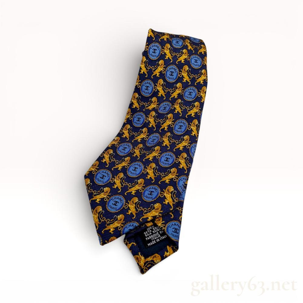 Description
Authentic Chanel Silk necktie featuring an allover chain and medallion pattern in blue and gold tones on a dark ground. Chanel Paris label present on the reverse. Standard pointed blade construction. Shows light wear consistent with use. Great for any Leos out there.