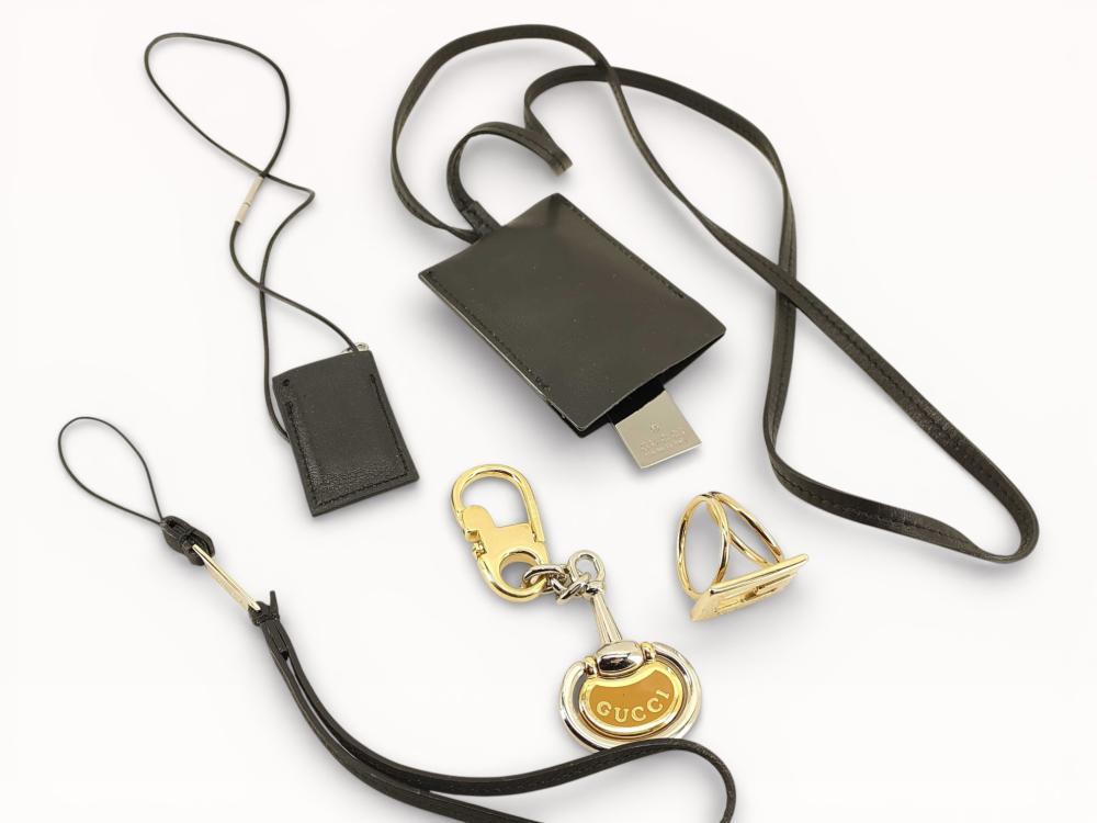 Description
A collection of Gucci and Hermes designer accessories including jewelry, keychains, and small leather goods. The group features a Gucci gold-toned architectural G logo ring, a two-tone horsebit keychain, a black leather neck pouch with a silver-toned metal insert, a leather accessory strap, and a Hermes silver-toned Amour pendant on a leather cord. All pieces feature visible maker marks including Gucci, Hermes, and Made in Italy stamps.
Ring: 2.5 cm width
Keychain: 11 cm length
Pouch: 9 cm x 6.5 cm
Strap: 10 cm length
Pendant: 4 cm x 2 cm.