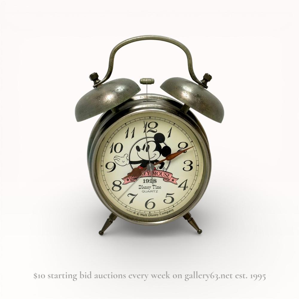 Description
Disney Time Mickey Mouse twin-bell quartz alarm clock, late 20th century. Metal case with a brushed silver-tone finish, mechanical twin-bell alarm, and cream dial featuring a Mickey Mouse illustration and 1928 banner. Dial and case back are marked Japan, and the side features Japanese licensing and sales permit stickers.
17 cm height, 12 cm width.