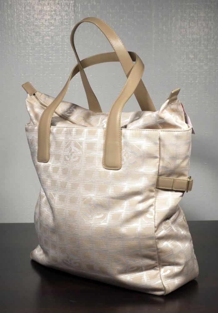 CHANEL

Sac cabas en toile siglée beige blanc, à effet de carreaux, fermeture éclair, double poignée cuir. Long: 35 cm