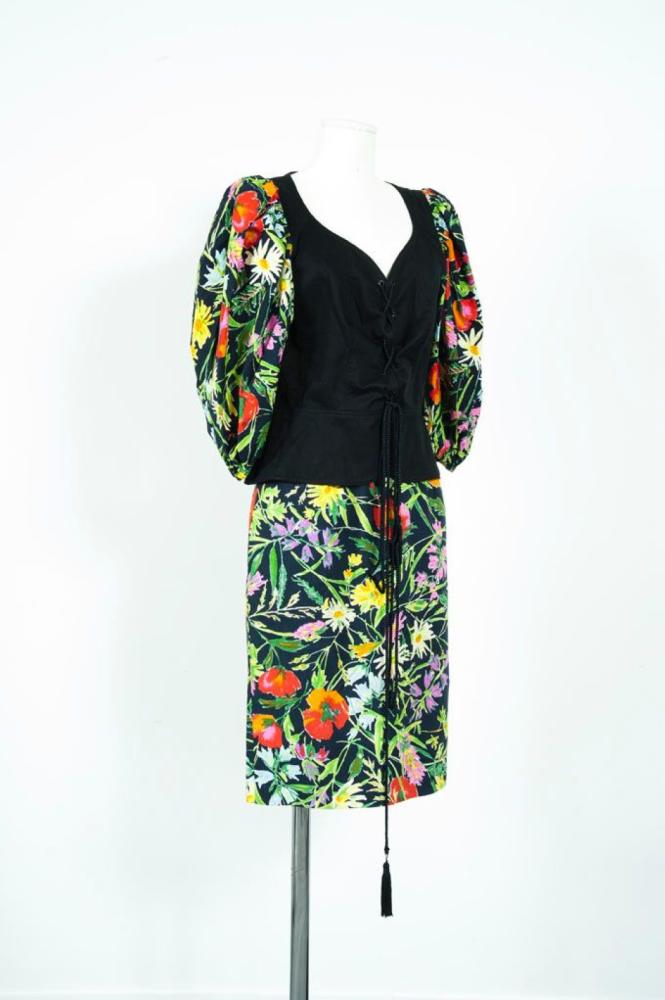 Yves SAINT LAURENT Variations

Ensemble composé d’un haut en coton noir décolleté précédant un lacet, demi-manches bouffantes en coton imprimé à motif florale multicolore sur fond noir, jupe droite à l’identique. Griffe blanche, graphisme noir