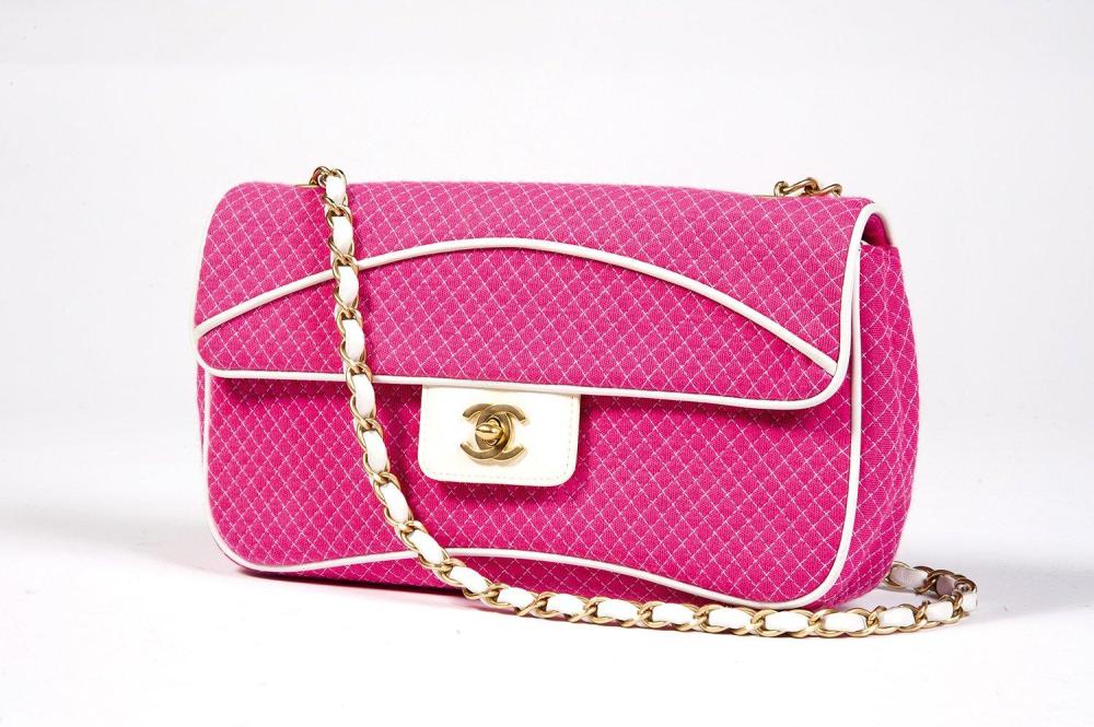 CHANEL

Sac 26cm en jersey matelassé rose à surpiqûres blanches, gansé de cuir en coordonné, fermeture en laiton doré sur rabat siglé en cuir vernis blanc, demi-anse bandoulière chaîne entrelacée de cuir à la couleur, poche extérieure. Bon état
