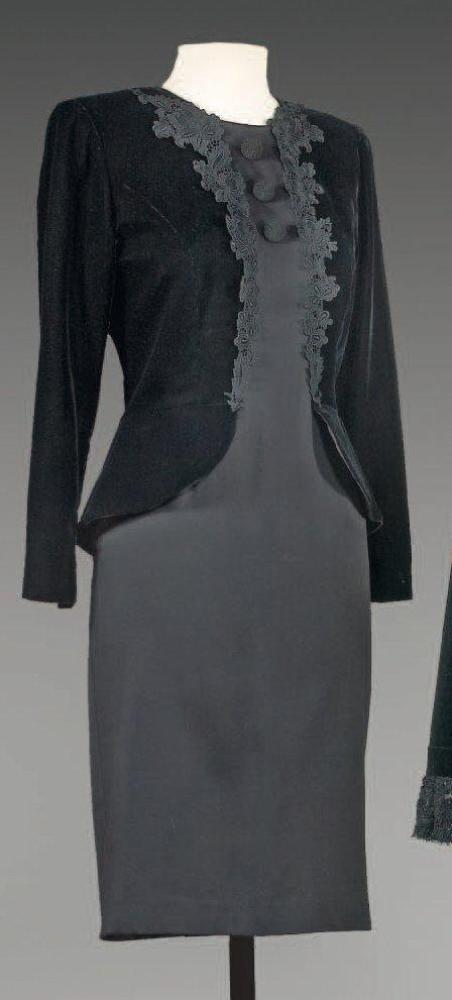 Mila SCHON, circa 1980

Robe de cocktail faisant faux deux pièces, haut figurant un spencer en velours noir gansé de guipure à encolure ronde, manches longues sur une robe en crêpe de laine et soie de même couleur, effet de boutonnage passementerie sur le buste. Griffe blanche, grpaphisme gris