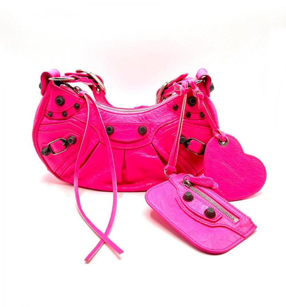 Description

BALENCIAGA.
Le Cagole XS bag.
Fuchsia pink leather with cracked texture characteristic of the Le Cagole line. Featuring dark silver-tone hardware, multiple decorative rivets and an adjustable strap that allows it to be worn over the shoulder or across the body. With antiqued metal details and removable accessories, such as the classic heart-shaped mirror and matching small purse.
The interior, lined in black fabric, is in good overall condition, as is the exterior, with minimal signs of use.
Measurements: 11 x 24 x 6 cm.

The fuchsia pink leather is a bold, contemporary style statement that pays homage to the brand’s rebellious heritage.

Le Cagole is a modern nod to Balenciaga’s iconic Motorcycle bags, reinterpreted with an ironic, feminine twist.