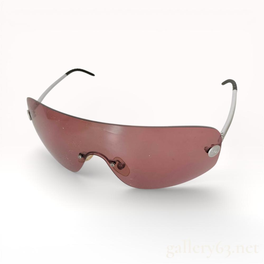 Description
Shield-style sunglasses by Chanel featuring a single curved lens in a rose-tinted hue. Slim metal arms terminating in black acetate tips. Temple hinges accented with circular Cocomark logo hardware. Lightweight construction with integrated nose bridge and minimal frame detailing, presenting a streamlined, modern profile.