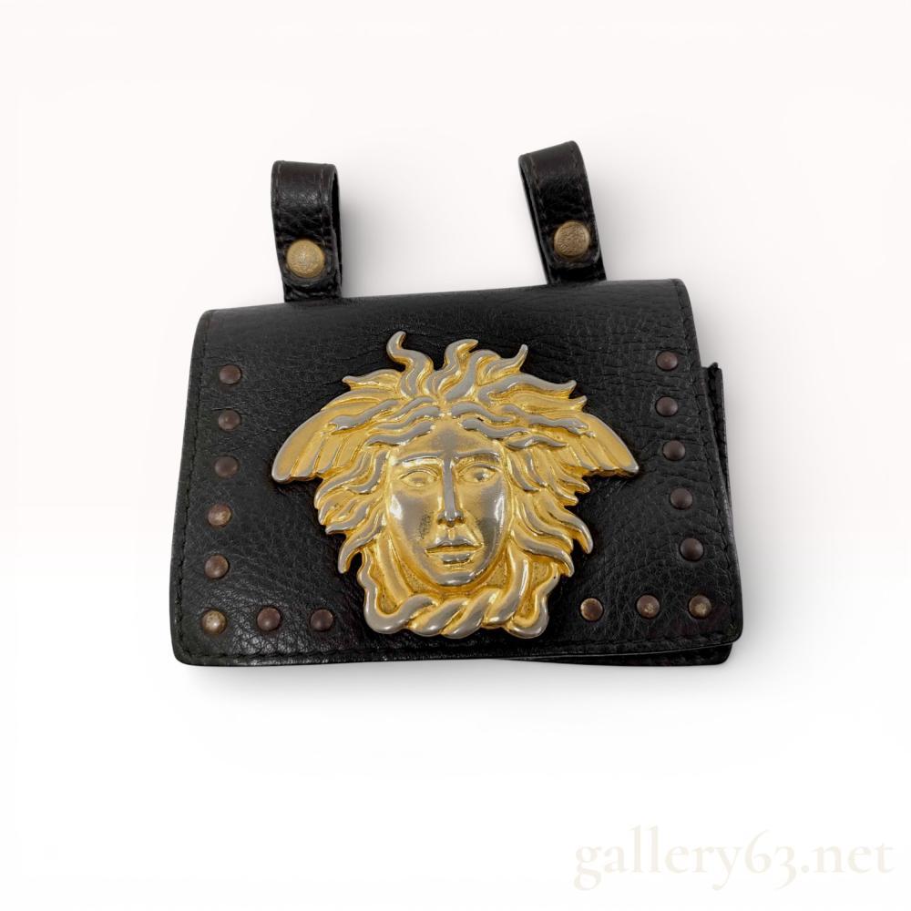 Description
Gianni Versace black leather belt pouch, circa 1994. The bag is crafted from pebbled leather with a suede-lined interior and features a large two-tone gold and silver-finish Medusa head plaque on the front flap. It includes snap-closure belt loops, a studded border, and an interior leather tag heat-stamped Gianni Versace Made in Italy 697 with Fiocchi Italy hardware.
Width: 5.1 in (13 cm)
Height: 3.7 in (9.5 cm).