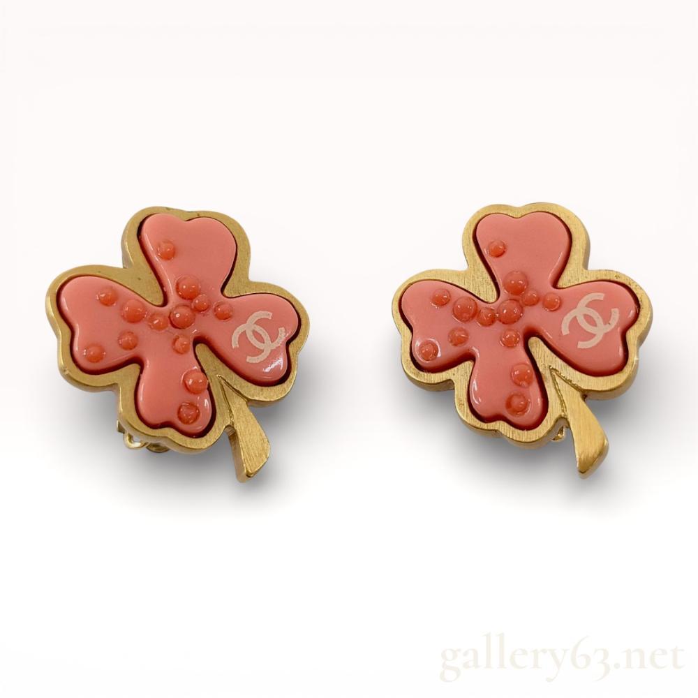 Description
Chanel clip-on earrings designed as stylized four-leaf clovers from the Spring 2003 collection. Each earring consists of a salmon-pink molded resin insert with raised circular granules and a white interlocking CC logo, housed in a gold-tone base metal frame. The reverse features a textured hammered finish and an oval authenticity plaque stamped CHANEL 03 P MADE IN FRANCE.
Approximately 2.5 cm x 2.5 cm.