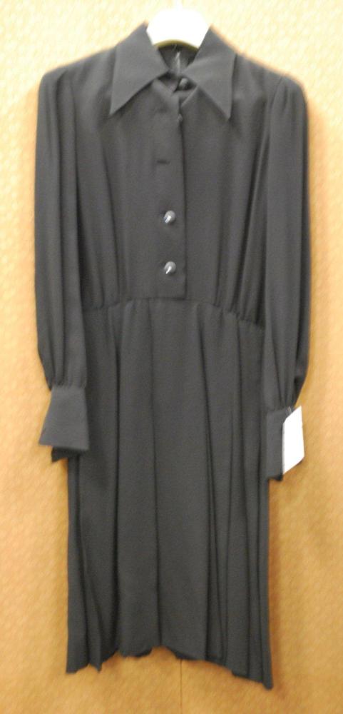 VALENTINO Couture, circa 1970 / 1975

Robe chemisier en crêpe de soie noir, col en pointe, buste à simple boutonnage, manches longues à poignets resserrés, jupe à plis plats à partir des petites hanches, Griffe blanche, graphisme noir