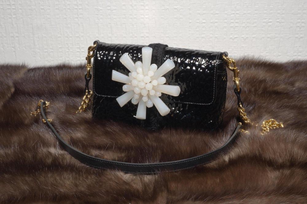 Marc JACOB

Petit sac en cuir vernis gauffré, fermoir aimanté sur rabat orné d’une fleurs en résine façon jade, anse bandoulière chaîne et cuir.