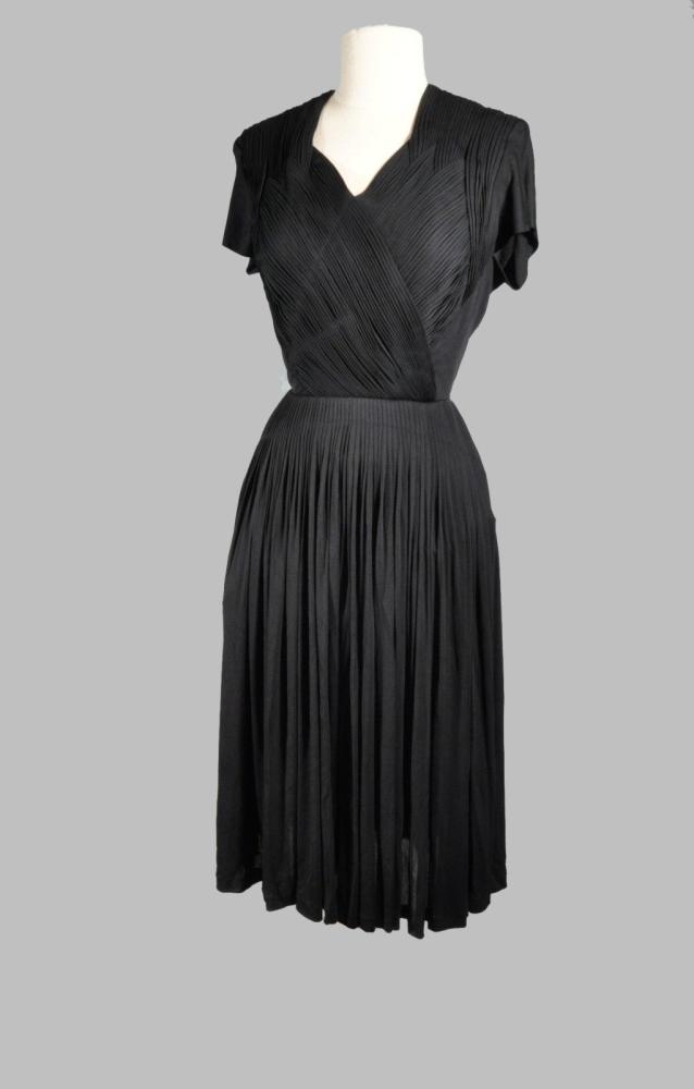 Une robe courte drapée en jersey noir avec...

Une robe courte drapée en jersey noir avec doublure postérieure, travail de plissé sur tout le corsage et la ceinture: attribuée à GRES 1945 (manque la griffe) provenance Madame de la Verteville, secrétaire de madame GRES.