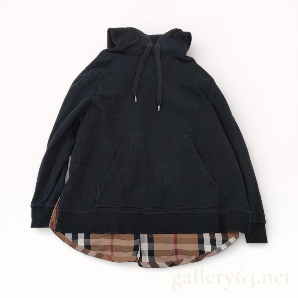 Description
Burberry Samuel cotton check-trimmed hoodie, contemporary. This black cotton jersey pullover features a drawstring hood, a central kangaroo pocket, and an attached House Check cotton panel extending from the hem to create a layered shirt-tail effect. Interior labels include a Burberry London England neck tag, an XS/TP size tag, and a multi-page care label confirming the garment was made in China.
Length: Approximately 28 inches.