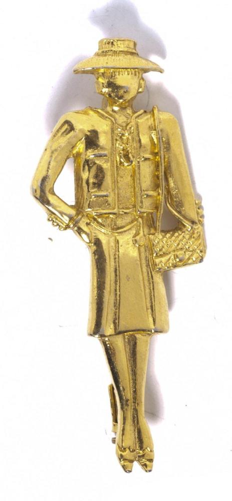 CHANEL

Broche en métal doré ciselé représentant Mademoiselle. Signée