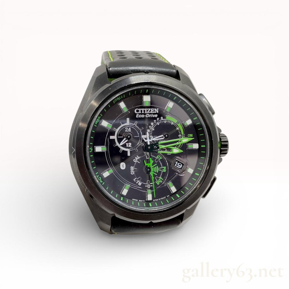 Description
Citizen Eco-Drive Proximity wristwatch, model AT7035-01E, featuring a Bluetooth-enabled caliber W760 light-powered quartz movement. The timepiece is constructed with a black ion-plated stainless steel case, a black dial with luminous markers and vibrant green accents, and a perforated black leather rally-style strap with green contrast stitching. The case back is incised with the Proximity logo, model W760, and serial number 2N1021189.
Case size: 44.1 mm.