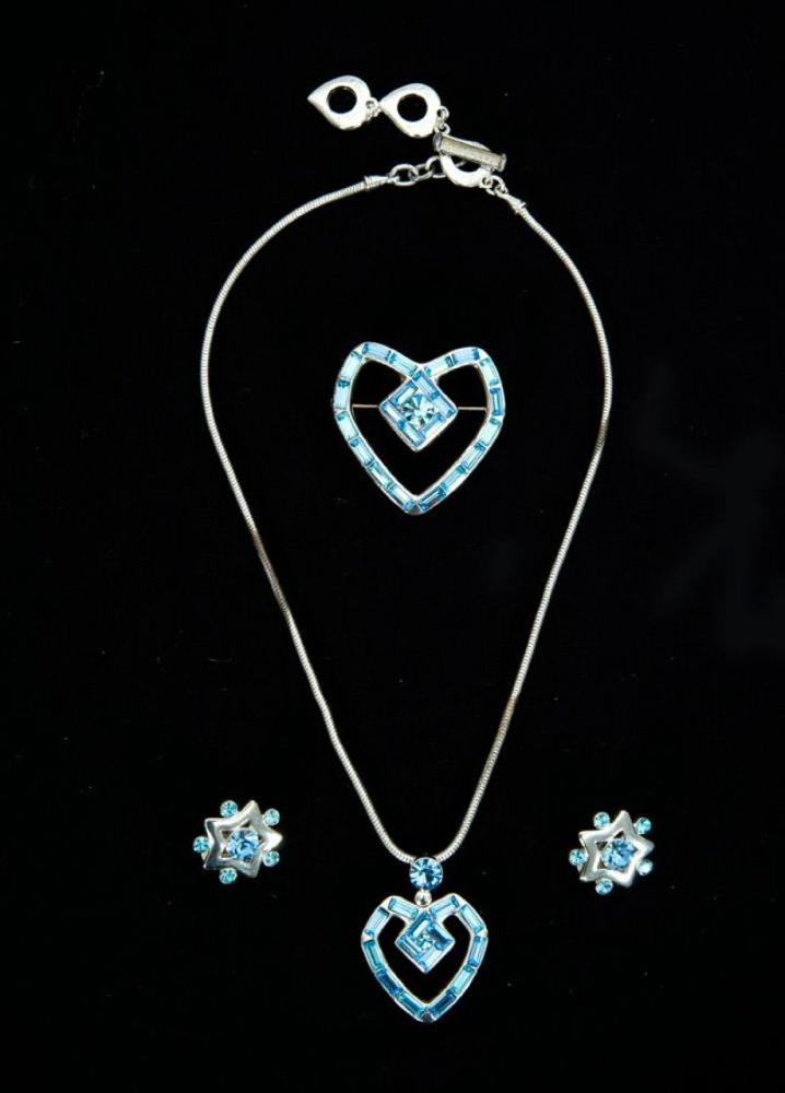 Yves SAINT LAURENT Made in France

Parure en métal argenté rehaussé de baguette façon aigue-marine certain de forme coeurs comprenant un collier tubogaz retenant un pendentif coeur, d’une broche et d’une paires de clips d’oreilles de forme étoile. Signés