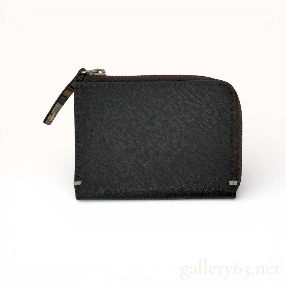 Description
Paul Smith coin case in black textured leather featuring a zip-around closure.


Rectangular case having a crosshatch-textured black leather exterior with stitched edges and small metal corner accents at the front base. Front embossed with Paul Smith.


Top zipper closure fitted with a multicolor striped pull tab and silver-tone hardware.


Interior lined in burgundy leather, featuring multiple compartments for coins and small essentials.


Brand: Paul Smith


Material: Textured leather


Color: Black exterior, burgundy interior


Closure: Zip-around with striped pull tab


Hardware: Silver-tone


Markings: Paul Smith embossed at front


Compact zip coin case rendered in signature Paul Smith styling with striped accent detail.