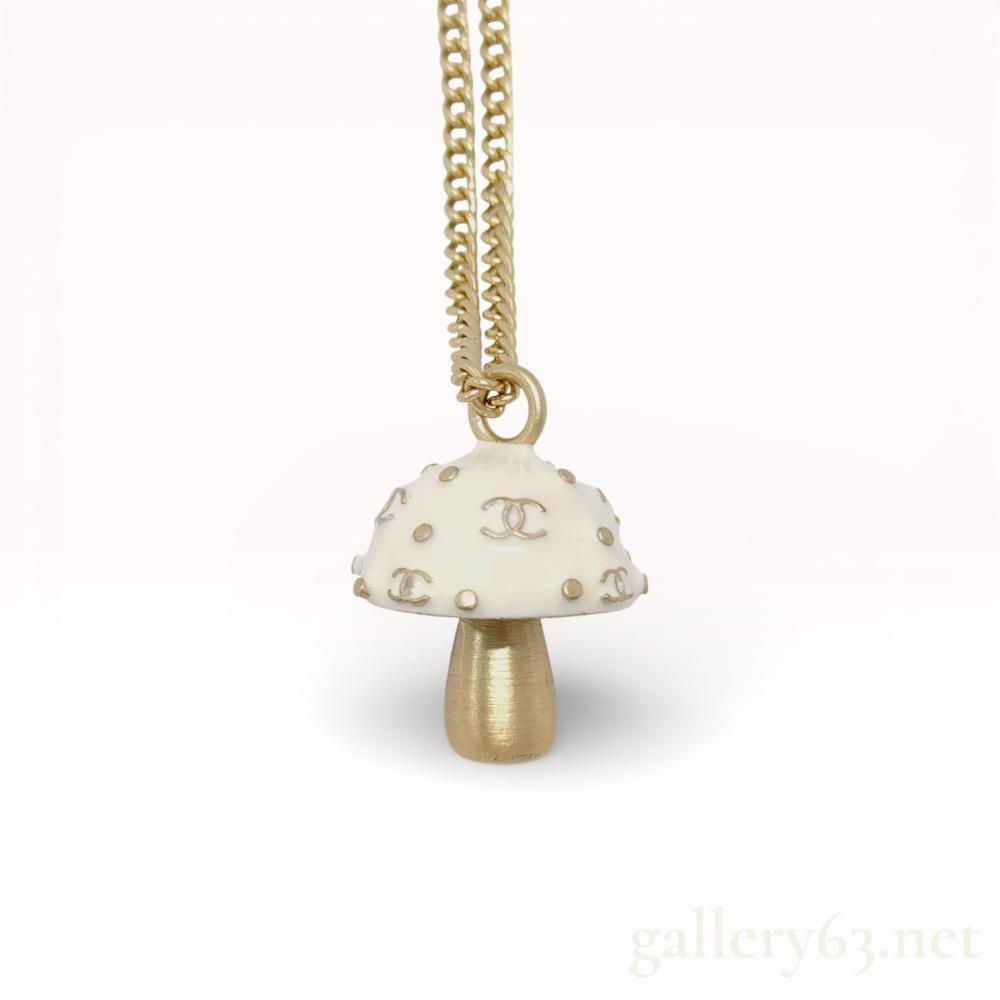 Description
NOTE: WE ALSO HAVE THE MATCHING BRACELET IN THIS AUCTION. Authentic Chanel mushroom pendant necklace from the Spring 2003 collection, featuring a sculptural mushroom-form pendant suspended from a gold-tone chain. Pendant having an ivory-toned cap set with repeating interlocking CC motifs and small stud accents, paired with a brushed gold-tone stem. Necklace finished with a classic Chanel chain and ring attachment, presenting a playful yet iconic example of early 2000s Chanel costume jewelry design.