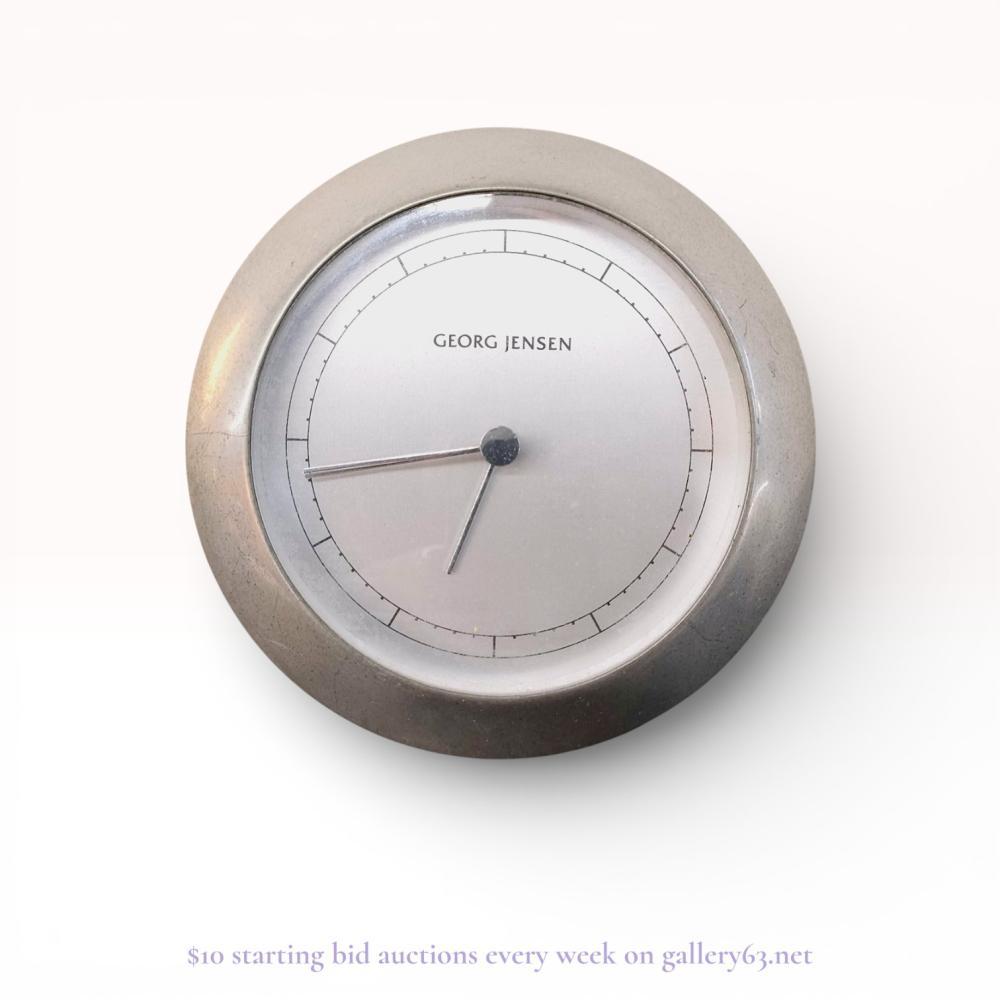 Description
Georg Jensen Venus series modernist quartz clock designed by Andreas Mikkelsen, late 20th century. The clock features a circular brushed metal case with a satin silver-tone dial, minimalist baton hands, and a printed minute track. It includes a detachable metal desk stand and is embossed on the reverse with the maker and designer names.
Diameter: 5.5 inches.