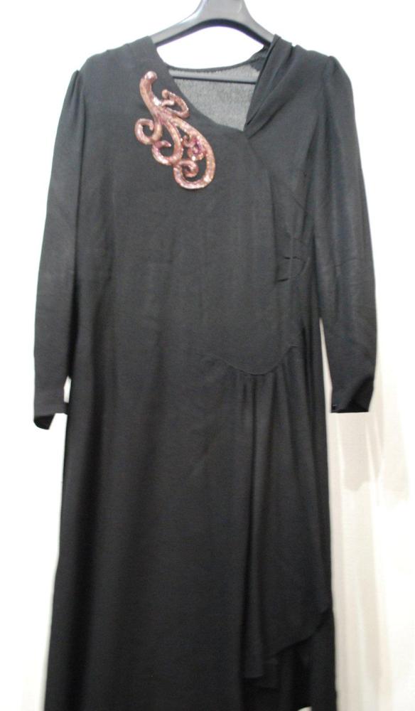 Anonyme

Robe longue en crêpe noir, décolleté asymétrique, épaule soulignée d’une application de paillettes violettes, dorés, taille soulignée d’une fronce et d’une ceinture, longueur asymétrique. Décousus