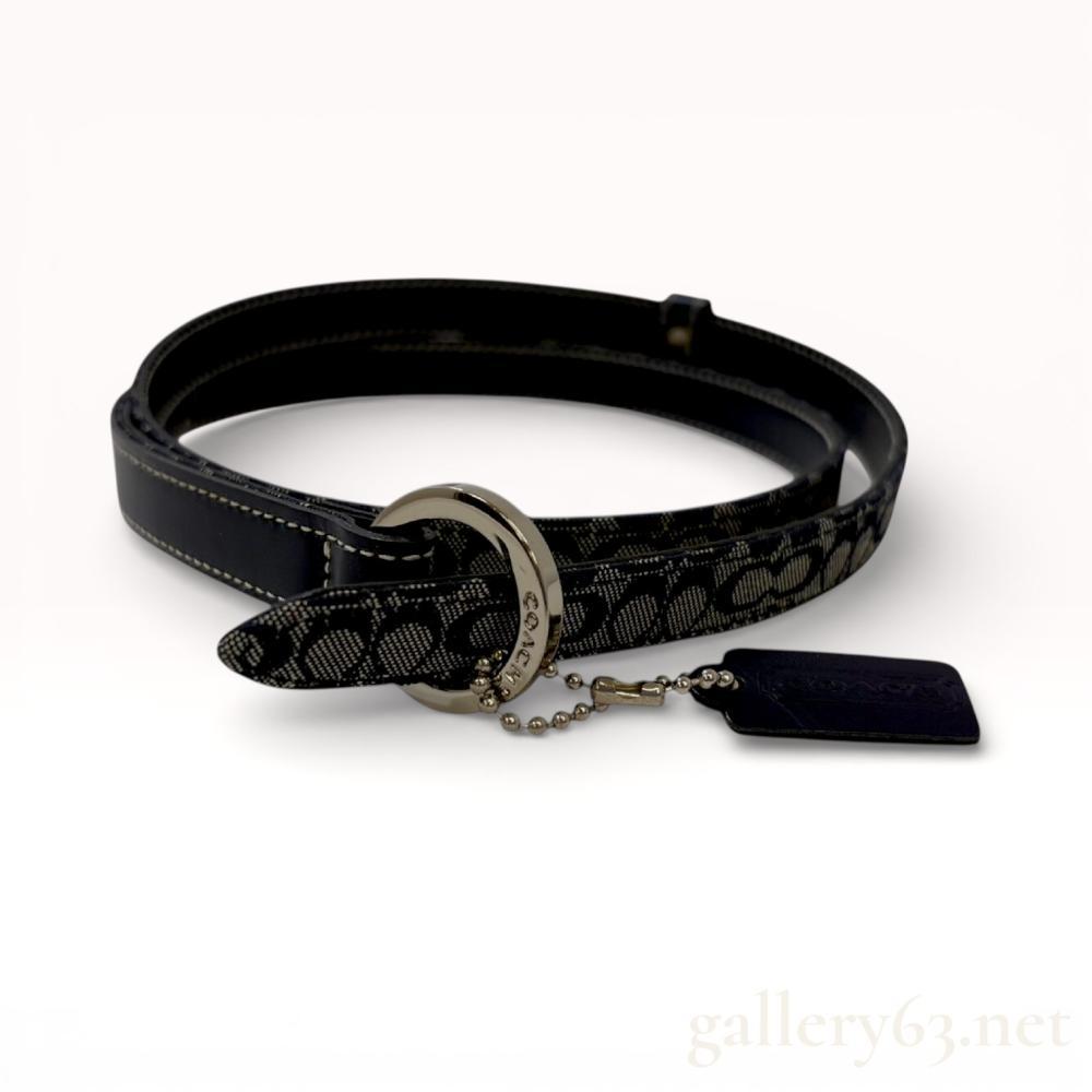 Description
Coach skinny belt featuring signature C logo jacquard canvas in charcoal and navy tones with a smooth leather lining. The design includes white contrast top-stitching, a single leather keeper, and a silver-tone D-ring buckle. A signature leather hangtag is attached to the buckle via a bead chain. The interior leather is embossed with the Coach cartouche and Made in Italy.