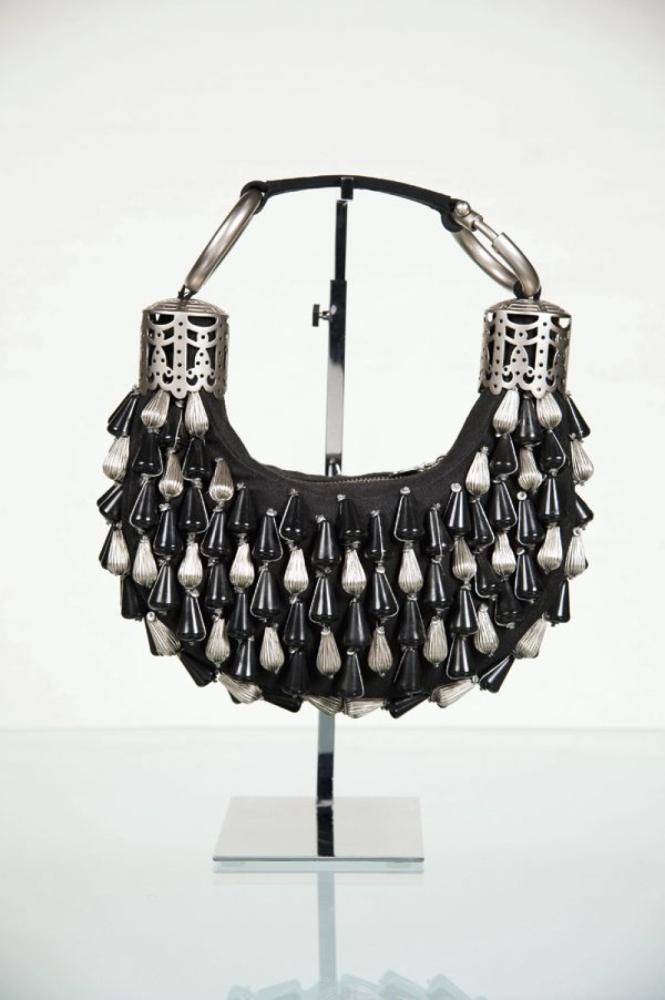 CHLOE

Sac demi-lune en coton noir, rehaussé de pompons en acier brossé et en composite noir, fermeture éclair, poignée retenue par deux anneaux en acier brossé surmontant deux motifs ajourés à l’identique. Bon état.