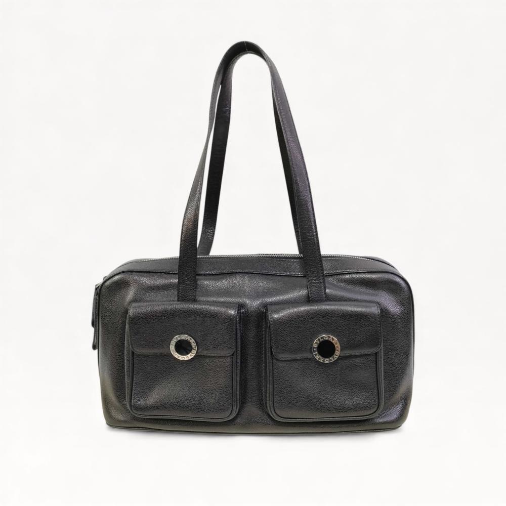 Description
Bulgari shoulder bag in black pebbled calfskin leather. Features dual front flap pockets with silver-tone circular hardware and a top zipper closure. The bag is finished with dual flat leather shoulder straps and bears the BVLGARI logo on the hardware and zipper pull.
14.5 inches width x 8 inches height.